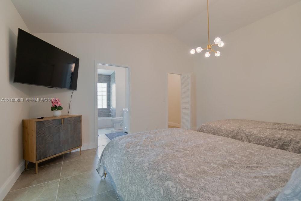 Vaulted ceilings, large-format tile flooring, and a contemporary multi-arm brass chandelier