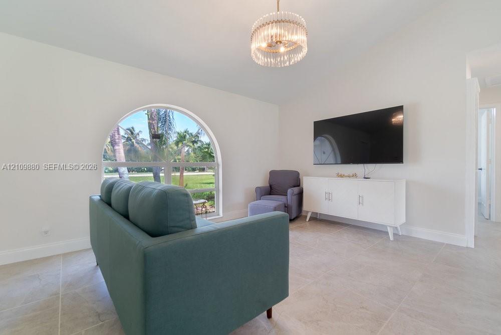 Arched window with exterior scenery, neutral tile flooring, and decorative multi-tier drum chandelier
