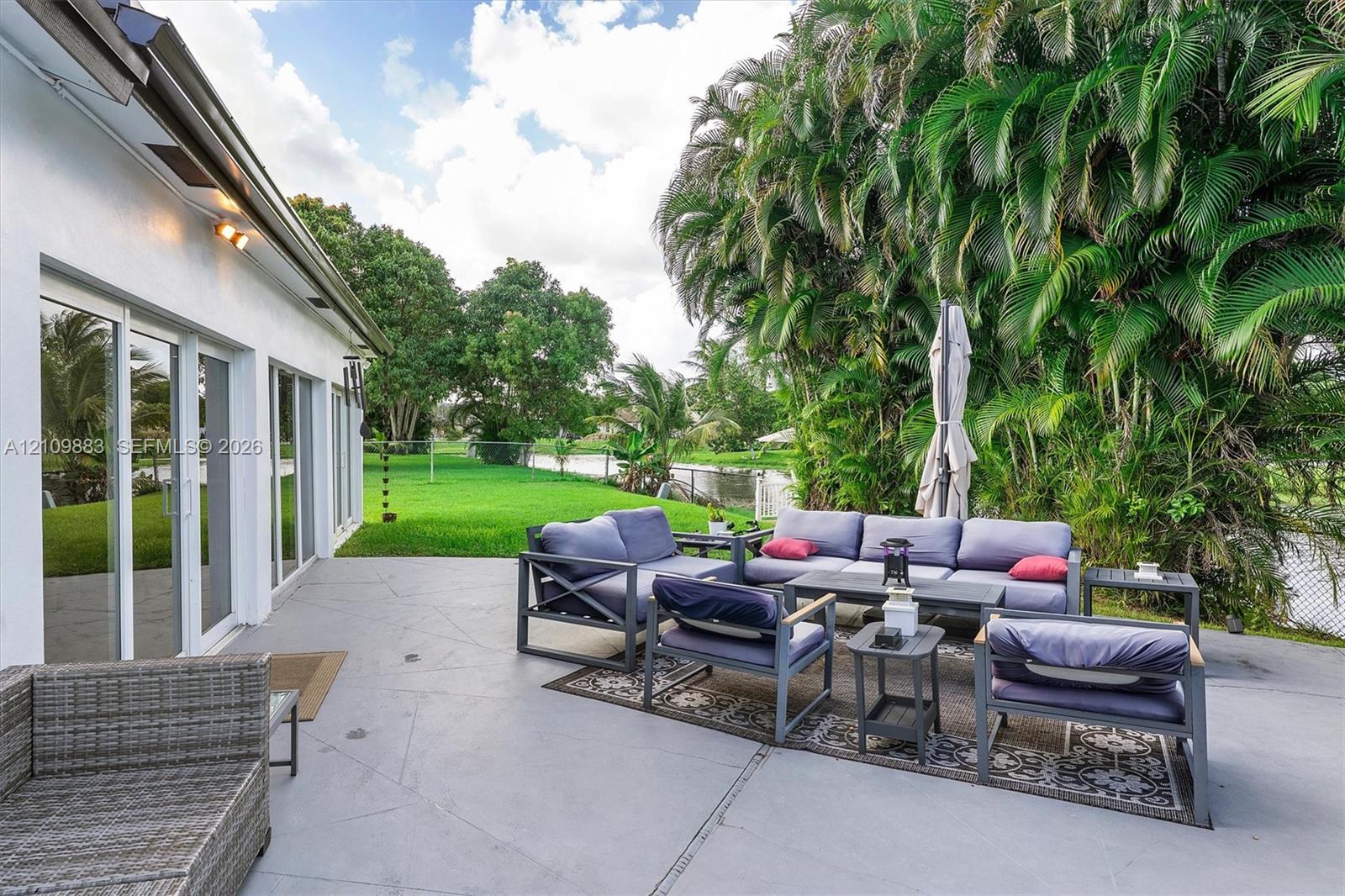 Concrete patio featuring sliding glass doors and expansive backyard greenery