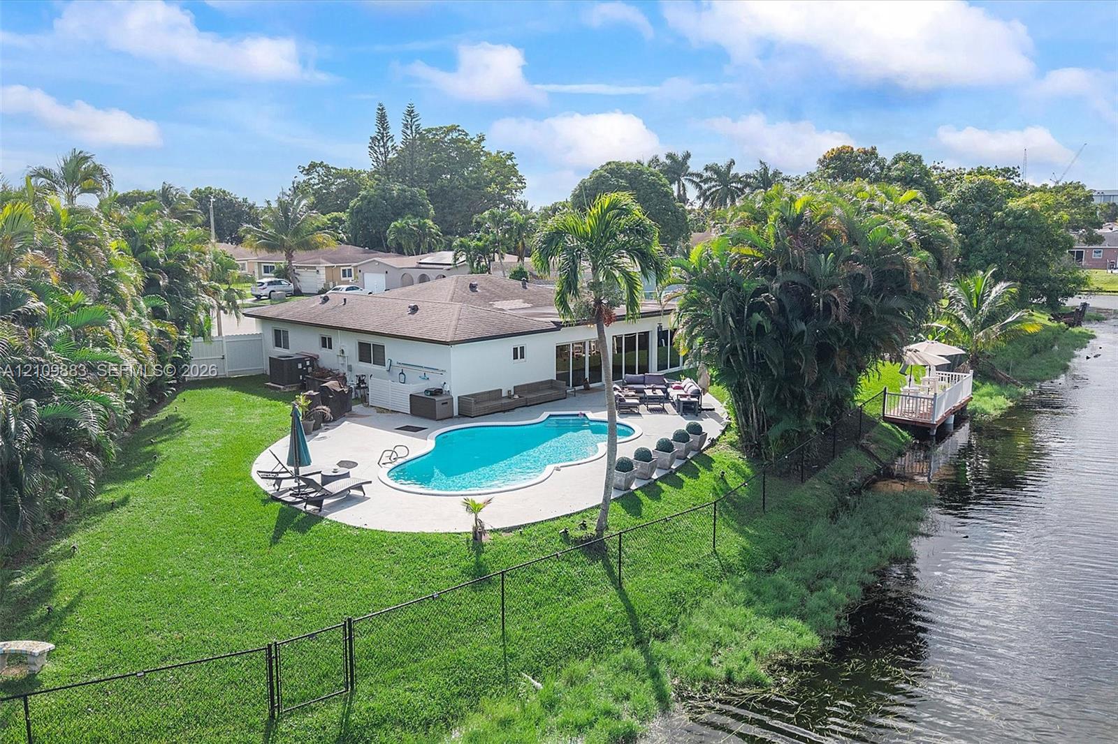 Waterfront property featuring a private swimming pool, expansive concrete patio, manicured lawn, and dedicated private dock