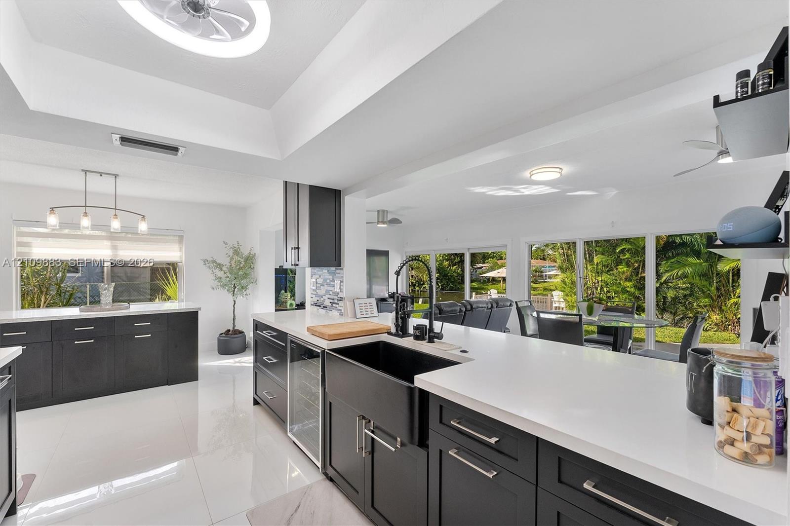Kitchen featuring dark cabinetry, expansive quartz countertops, a matte black farmhouse sink with a coordinating high-arch faucet, and a built-in wine cooler