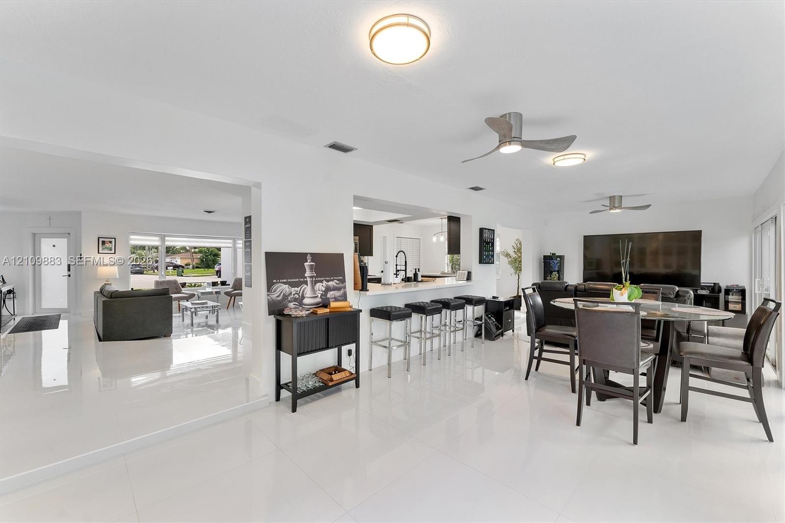 Open concept interior featuring polished tile flooring, recessed lighting, ceiling fans, and a kitchen peninsula with bar seating