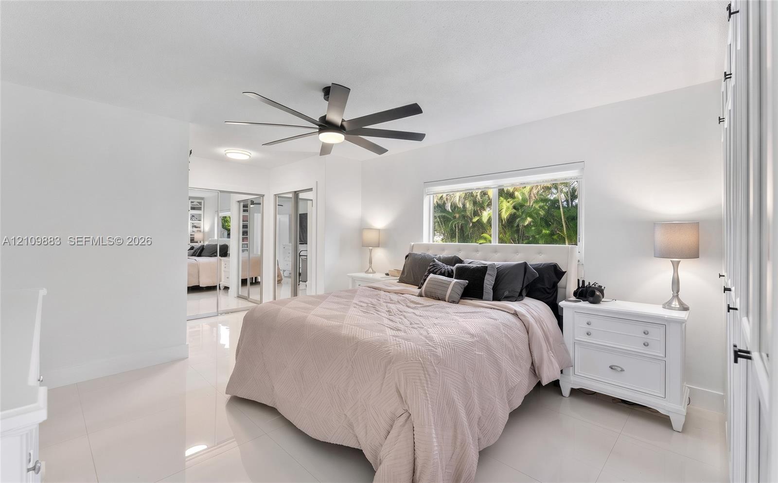 Spacious room featuring polished tile flooring, a multi-blade ceiling fan, and mirrored sliding closet doors
