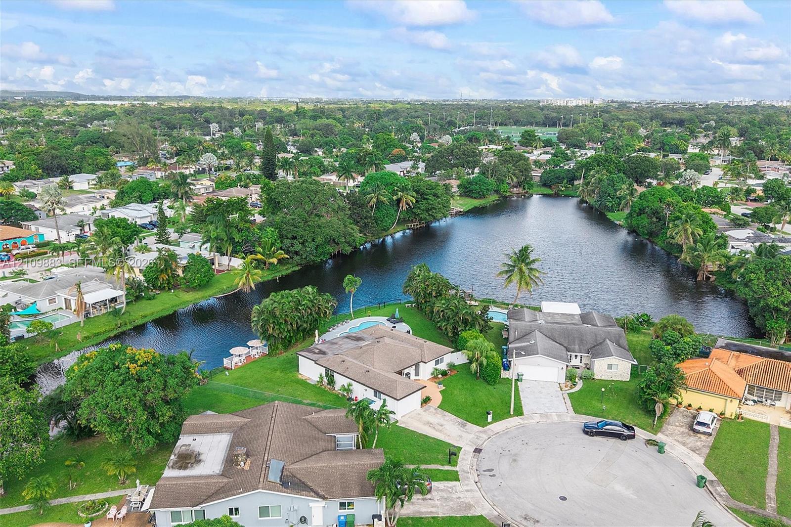 Aerial perspective featuring expansive waterfront positioning, cul-de-sac placement, mature landscaping, and private in-ground pools