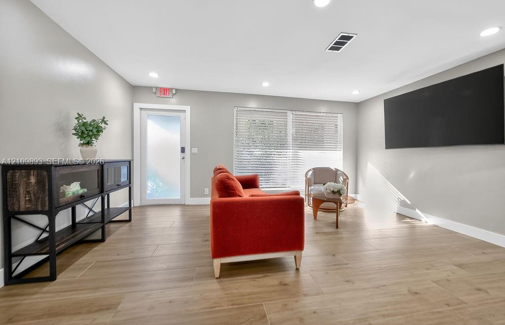Open floor plan featuring wood-finish flooring, recessed lighting, and horizontal window blinds