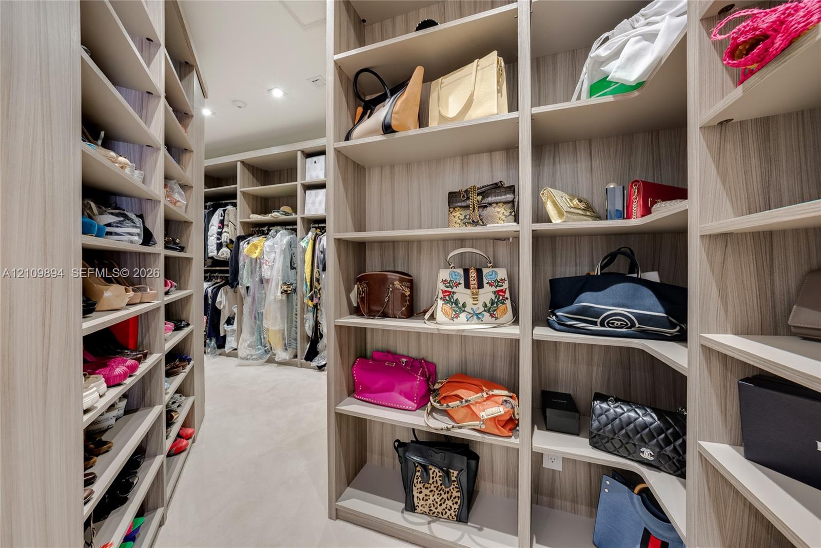 Walk-in closet featuring extensive custom wood-finish built-in cabinetry, multiple open shelving units, and integrated hanging racks