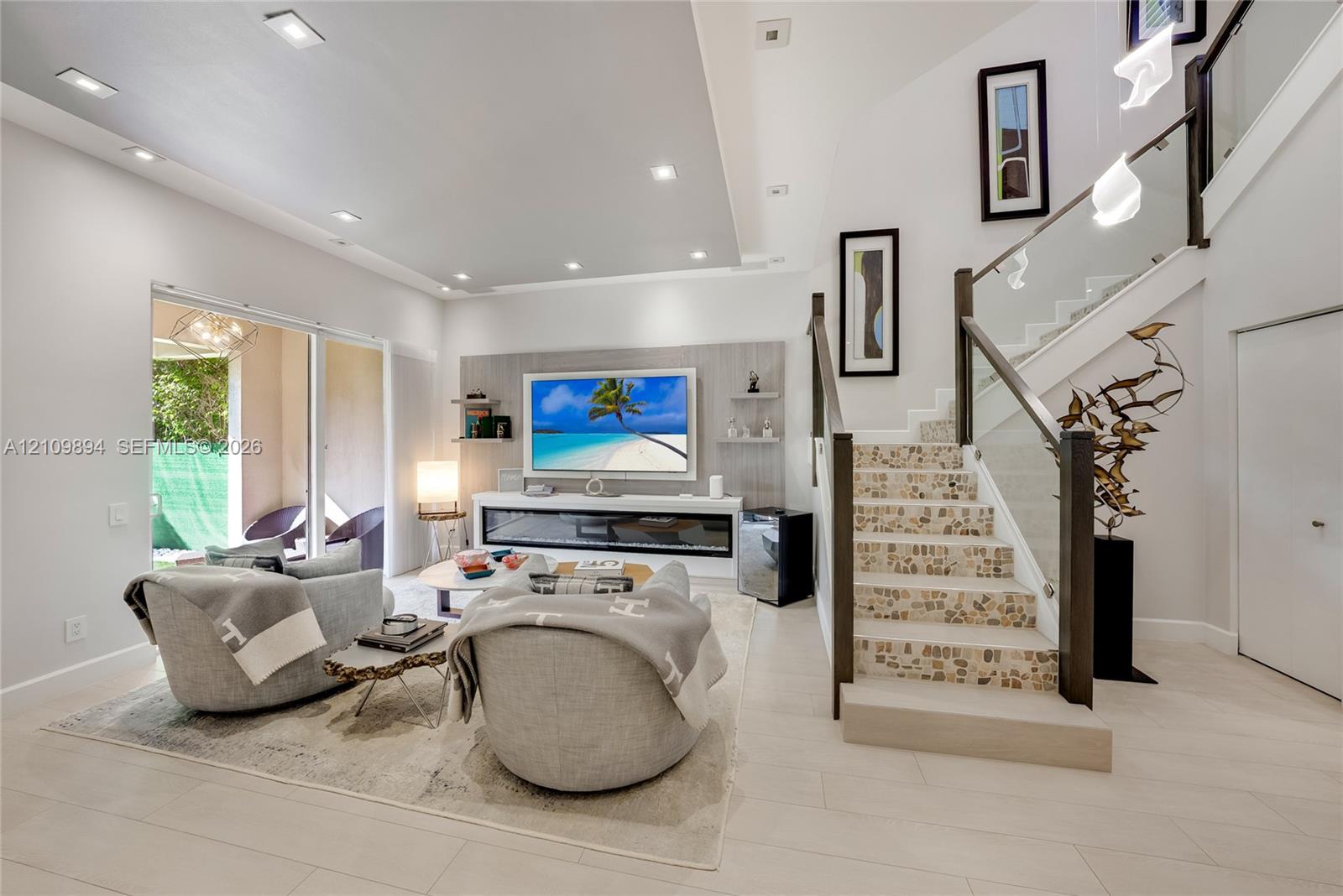 Living area featuring recessed lighting, a built-in linear fireplace with surround shelving, tile-finish flooring, and a staircase with glass railings and decorative stone-tile treads