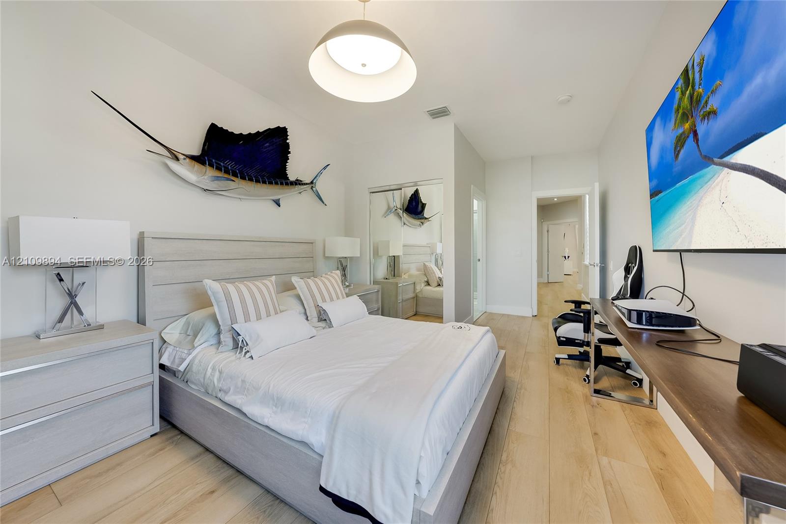 Room featuring wood-finish flooring, recessed lighting, a modern pendant light fixture, and floor-to-ceiling mirrored closet doors Room featuring wood-finish flooring, recessed lighting, a modern pendant light fixture, and floor-to-ceiling mirrored closet doors