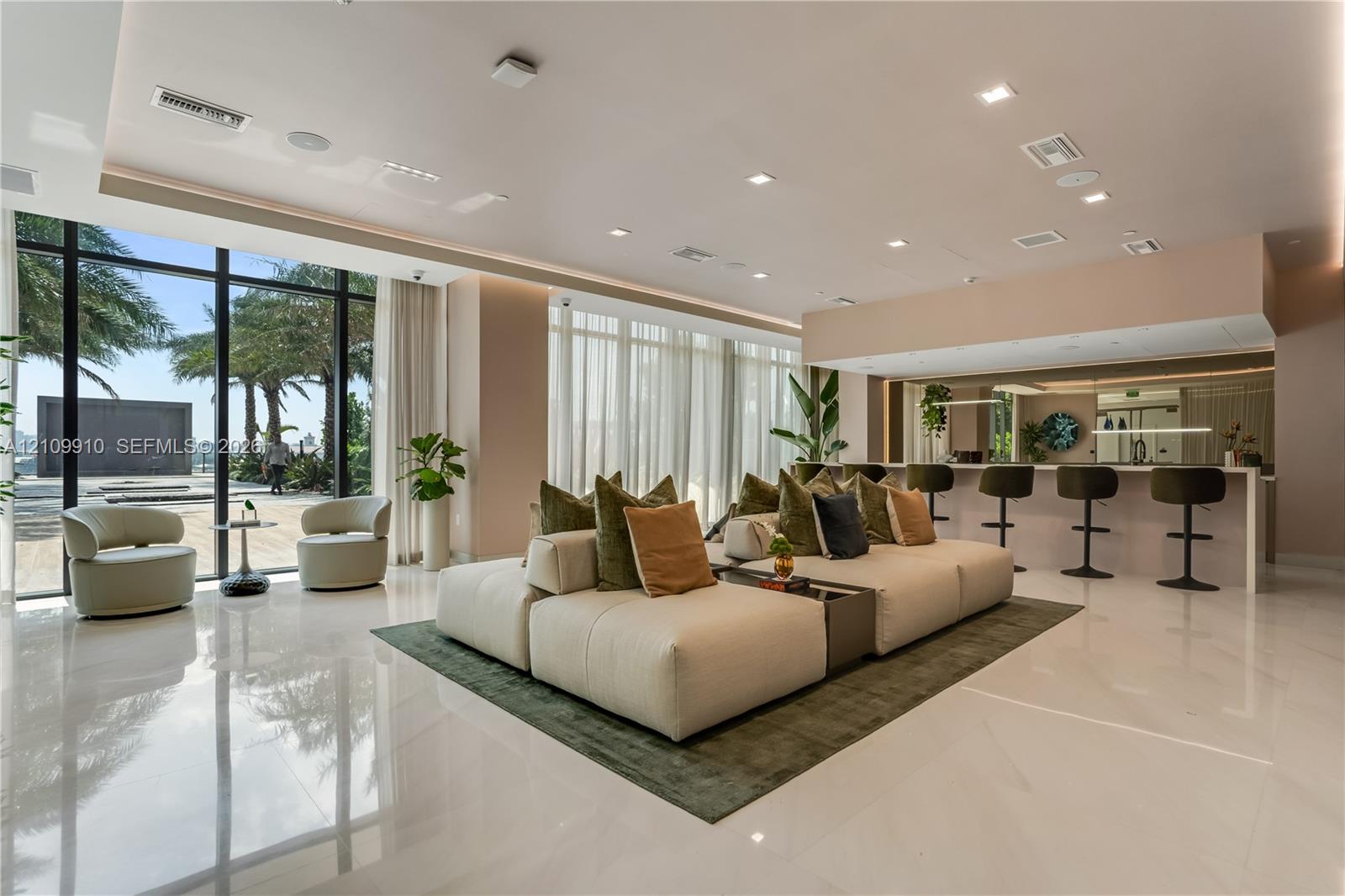Open-concept interior featuring floor-to-ceiling windows, polished stone flooring, recessed ceiling lighting, and a built-in bar area with stone countertops