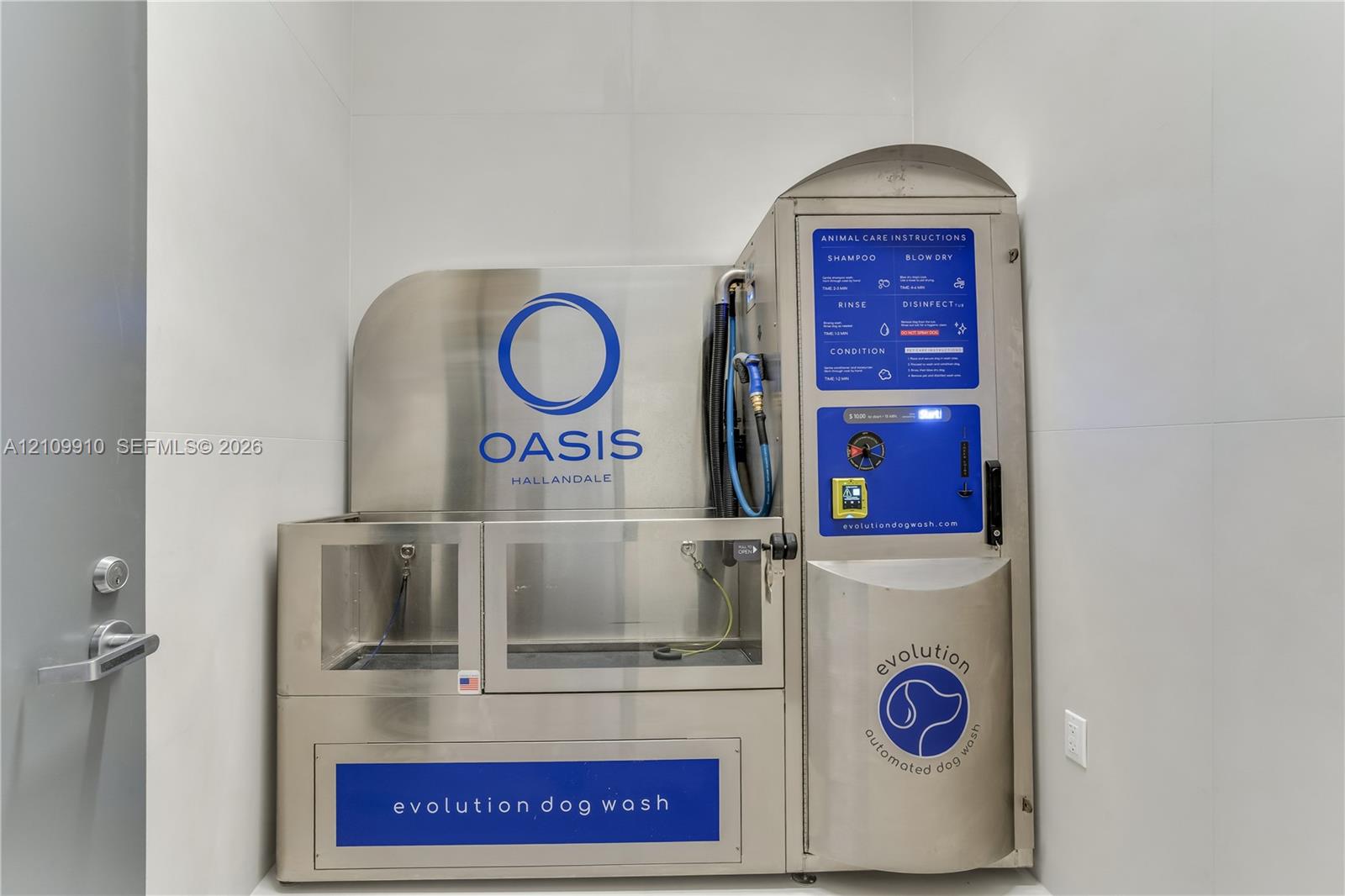 Stainless steel automated pet washing station featuring a built-in spray nozzle, integrated control panel, and large-format wall tiling