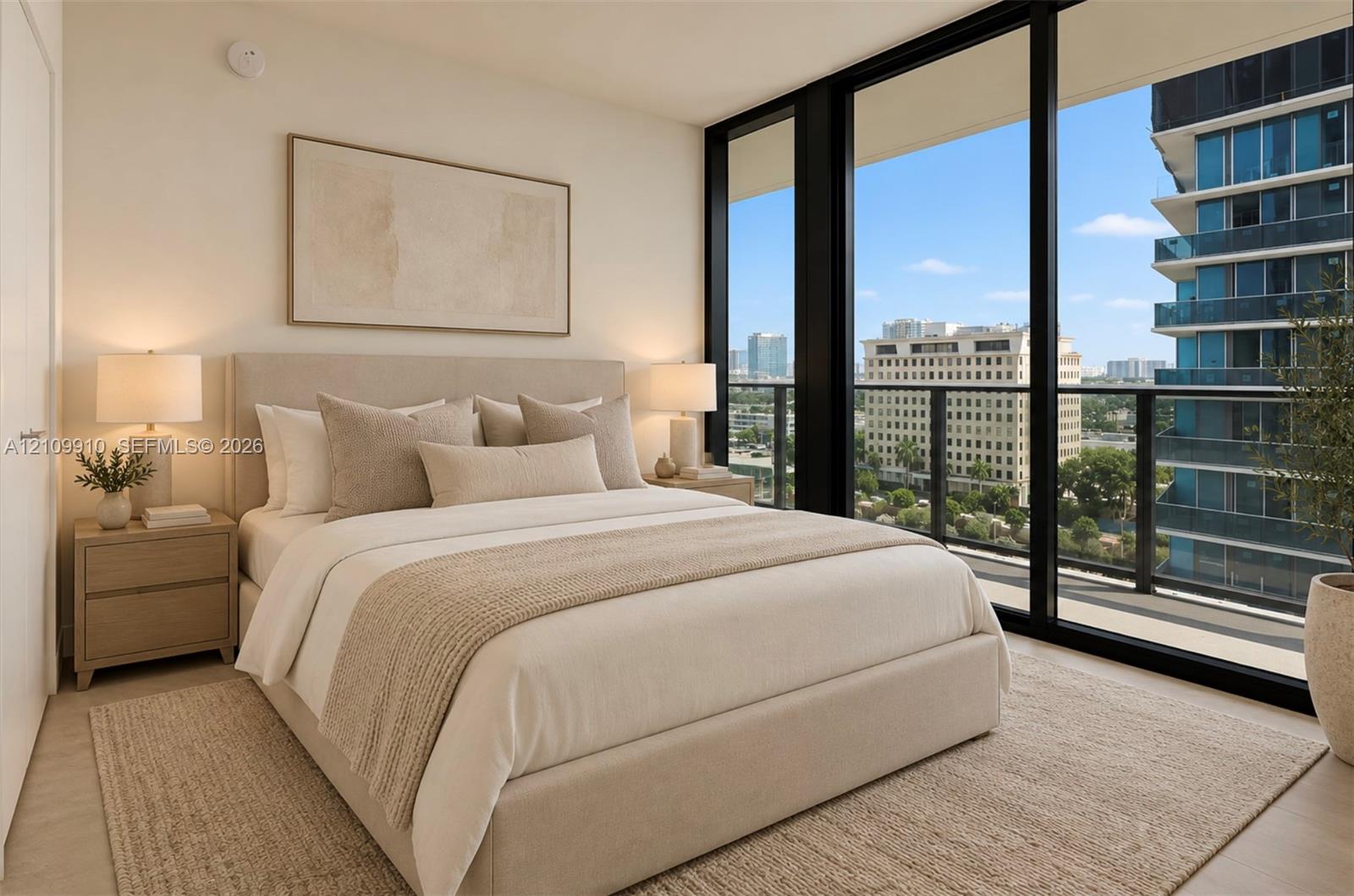 Floor-to-ceiling windows featuring urban scenery and access to an exterior balcony with a metal railing, complemented by neutral-toned interior walls and wood-finish flooring