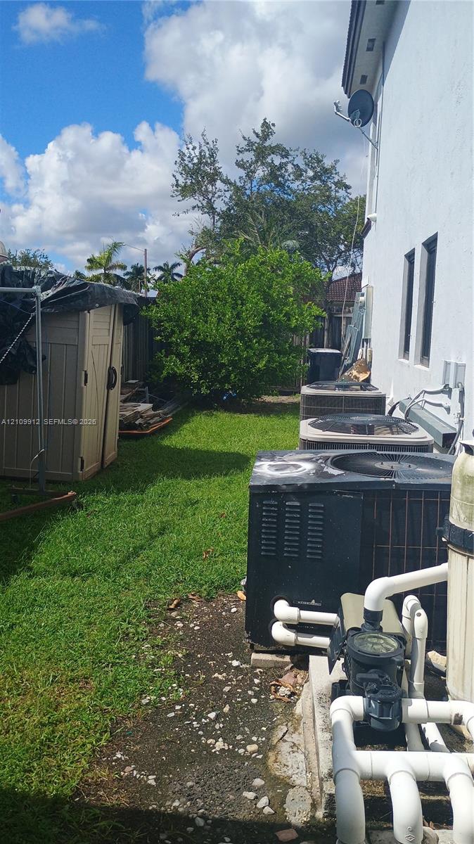 Side yard featuring grass landscaping, mature trees, and exterior HVAC condenser units
