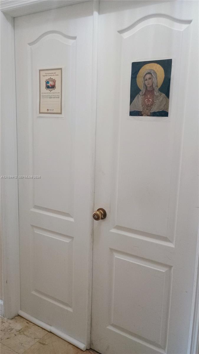 White double-panel closet doors featuring arched top rails and a brass-finish round knob
