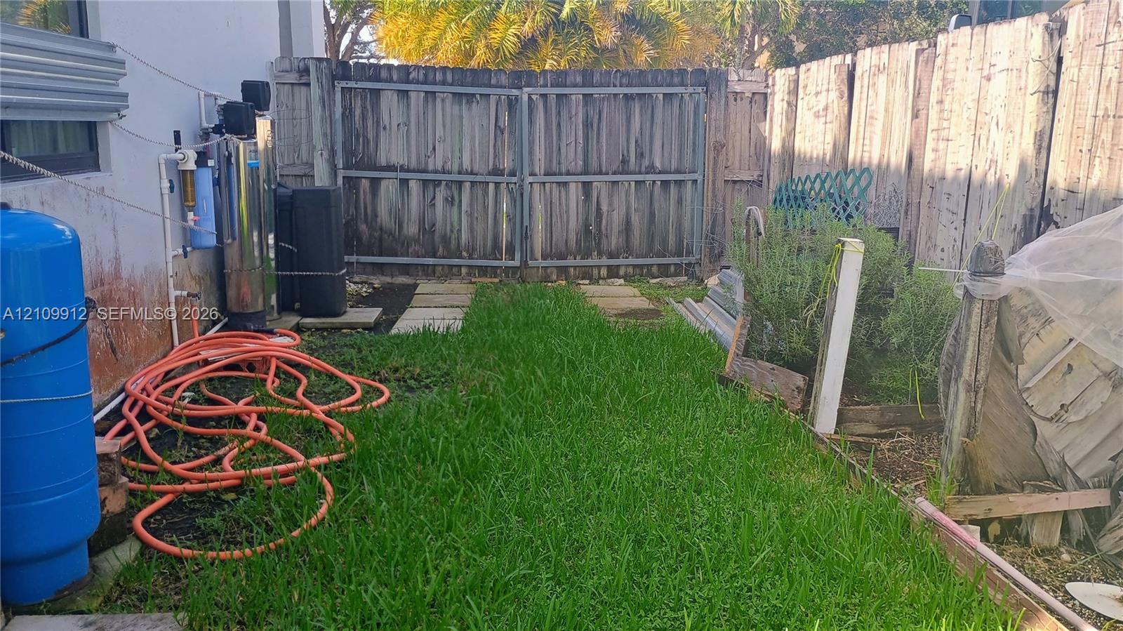 Outdoor area featuring a wood privacy fence, double-gate access, concrete paver path, and lawn space