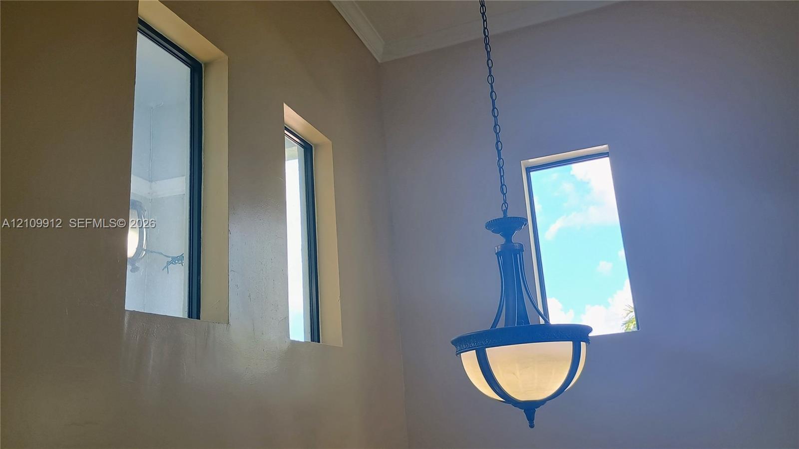 High-ceiling space featuring multiple tall rectangular windows and a tiered metal pendant light fixture with frosted glass shades