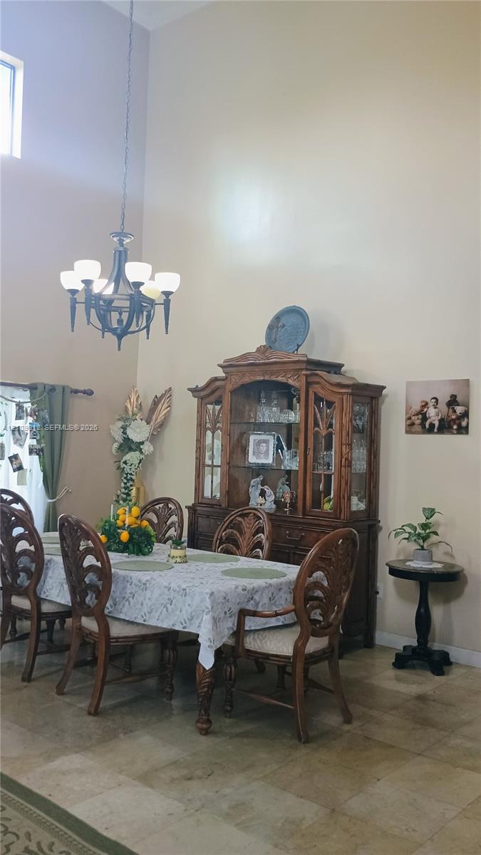 High-vaulted ceiling, neutral wall palette, stone-finish tile flooring, and multi-light chandelier fixture