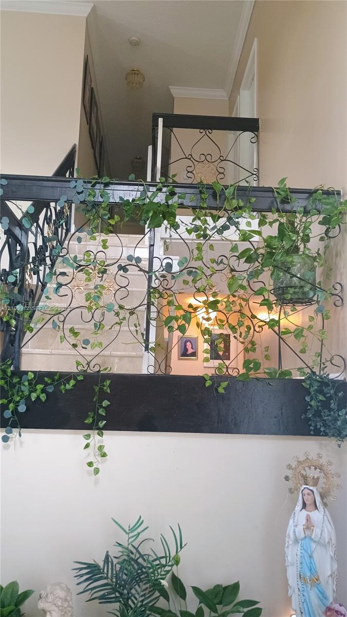 Ornate decorative metal balustrade featuring intricate scrollwork and a dark finish, complemented by crown molding and high-ceiling architecture