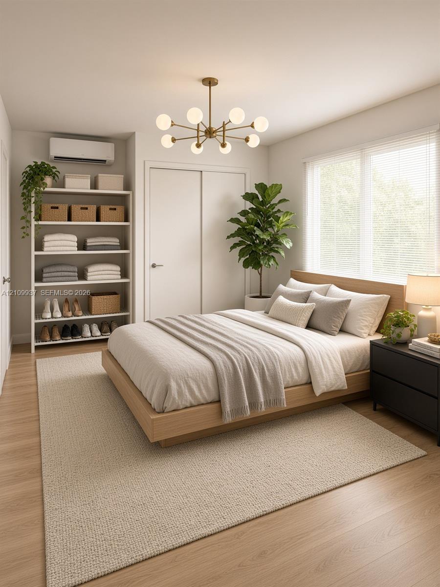 Multi-arm brass globe chandelier, wood-finish flooring, wall-mounted climate control unit, and window with blinds