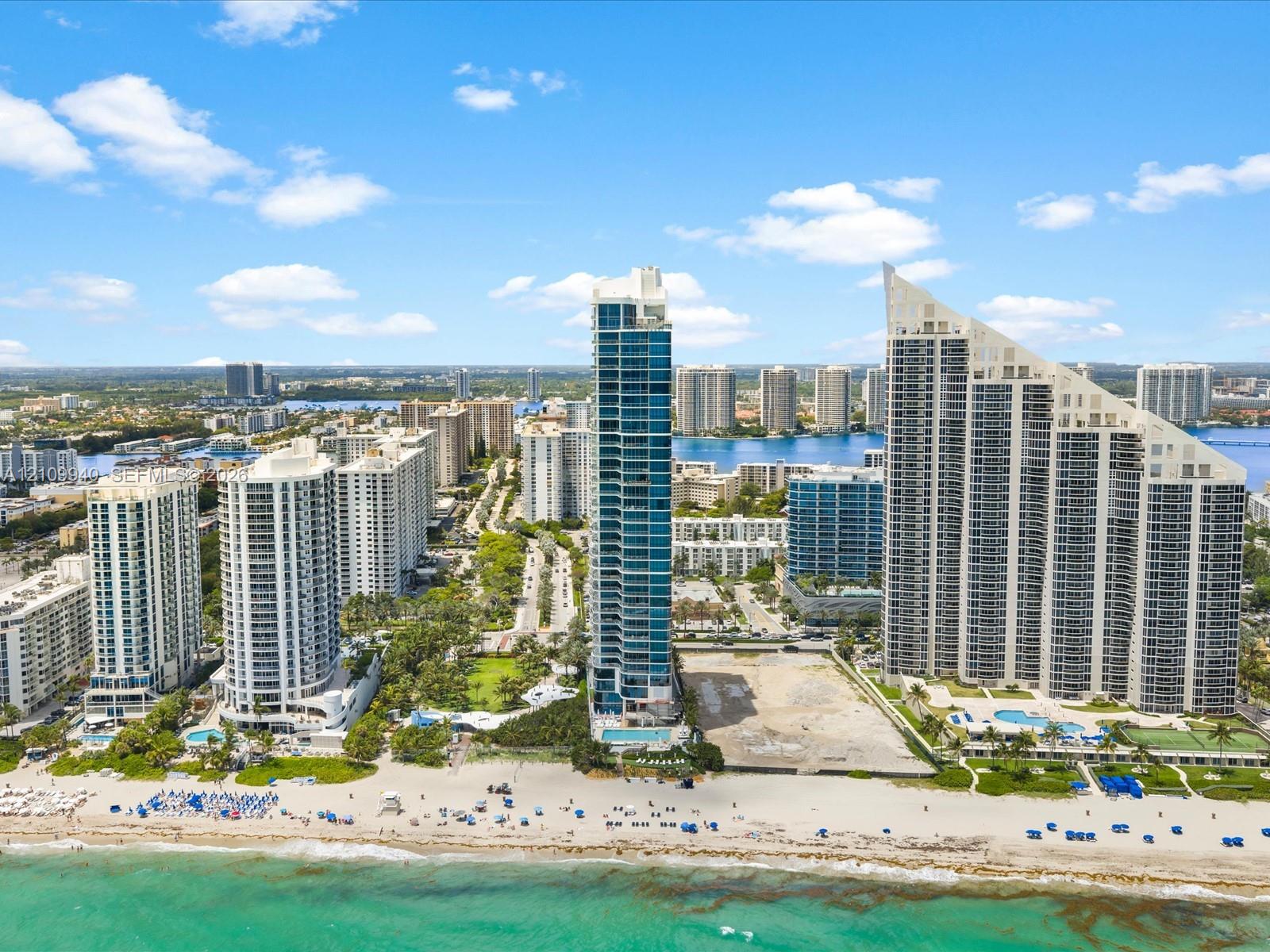 Coastal high-rise buildings situated along a sandy beach shoreline with direct ocean access and expansive waterfront scenery