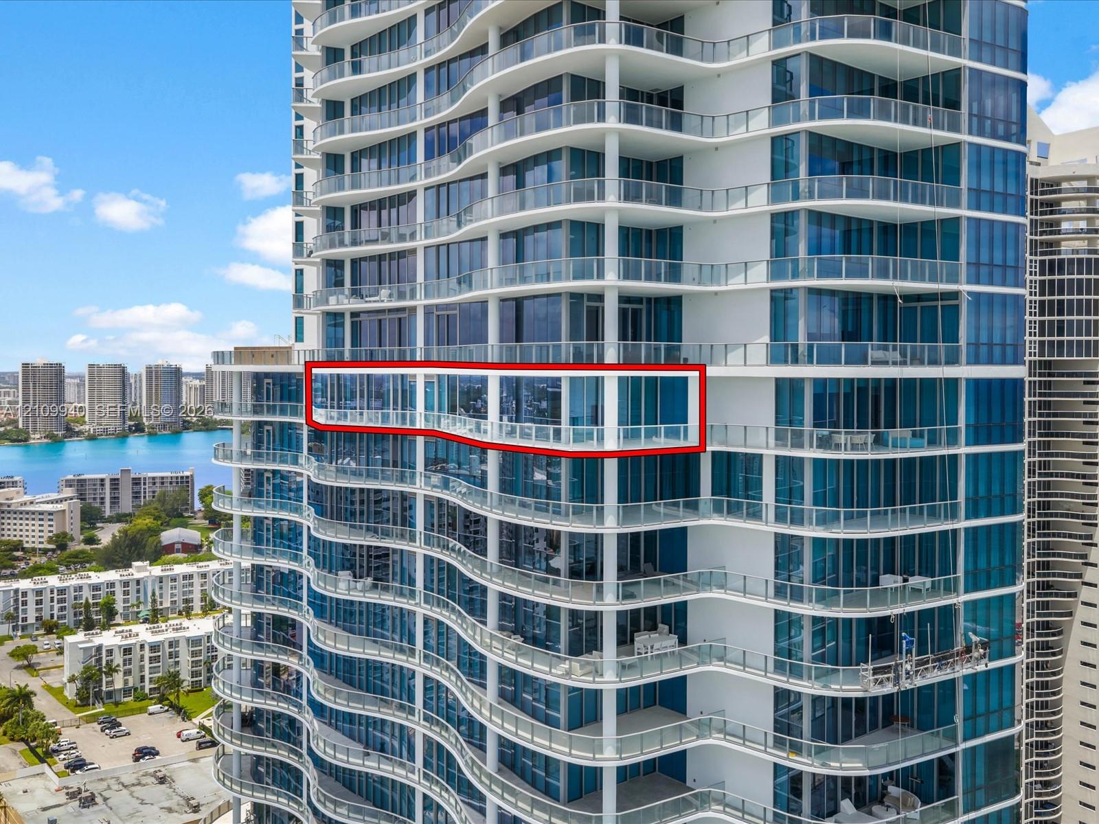 High-rise exterior featuring floor-to-ceiling glass windows and a wrap-around balcony with glass railings