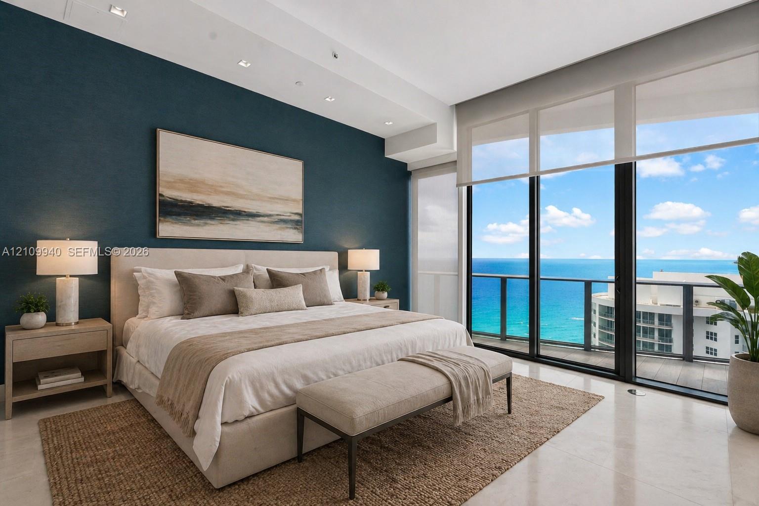 Floor-to-ceiling windows, polished stone flooring, recessed ceiling lighting, and a glass-railed balcony with ocean scenery