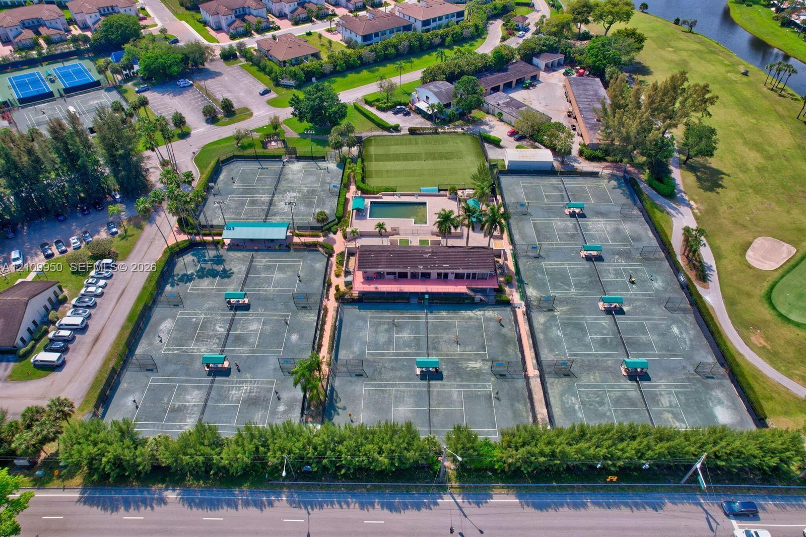 Aerial perspective of a recreation complex featuring multiple tennis courts, a swimming pool, a central clubhouse, and landscaped grounds