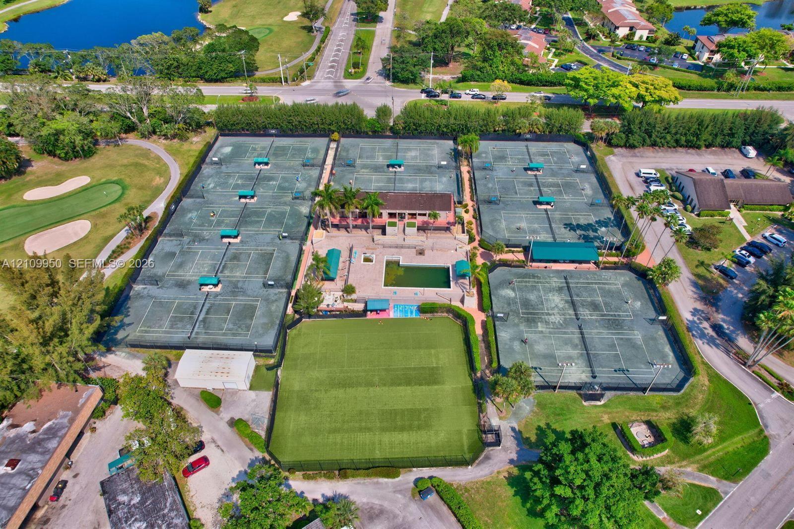 Recreational complex featuring multiple tennis courts, a swimming pool, a turf field, and a central clubhouse