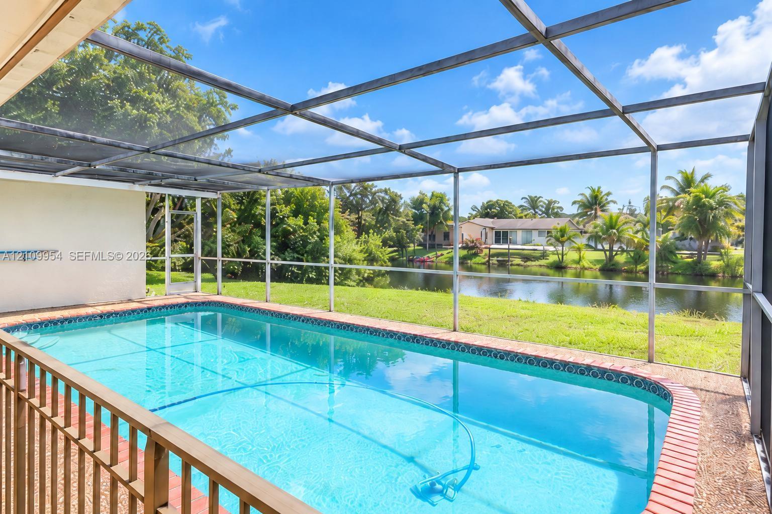 Screen-enclosed swimming pool featuring a brick paver perimeter and direct water frontage Screen-enclosed swimming pool featuring a brick paver perimeter and direct water frontage