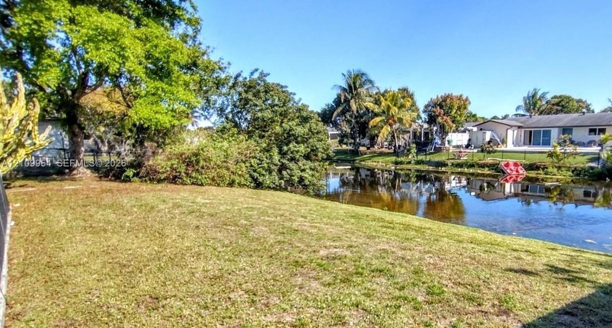 Expansive backyard featuring a grass lawn, mature trees, and direct water frontage