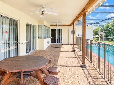 Covered patio featuring an aggregate concrete floor, ceiling fans, wood-support columns, and a screened enclosure surrounding a swimming pool