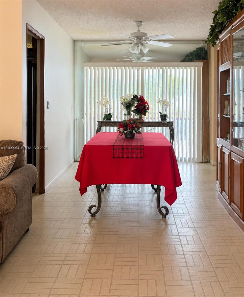 Ceramic tile flooring, built-in wooden cabinetry with glass-front shelving, ceiling-mounted light fixtures with integrated fans, and full-height vertical window blinds Ceramic tile flooring, built-in wooden cabinetry with glass-front shelving, ceiling-mounted light fixtures with integrated fans, and full-height vertical window blinds