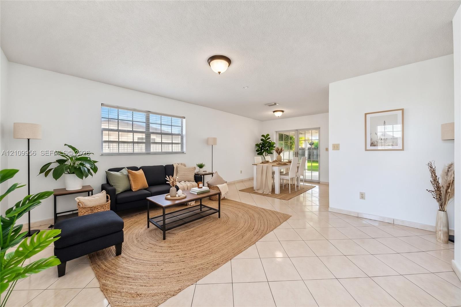 Open-concept interior featuring light-colored tile flooring, flush-mount ceiling lighting, large windows, and sliding glass doors