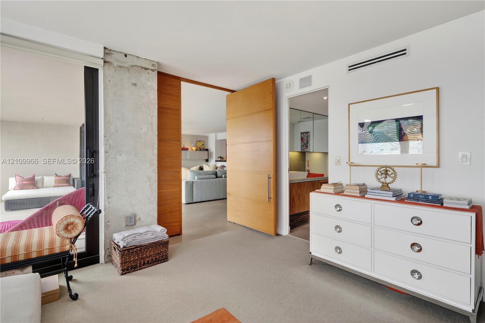 Exposed concrete column, solid wood oversized interior door, and floor-to-ceiling glass sliding panels