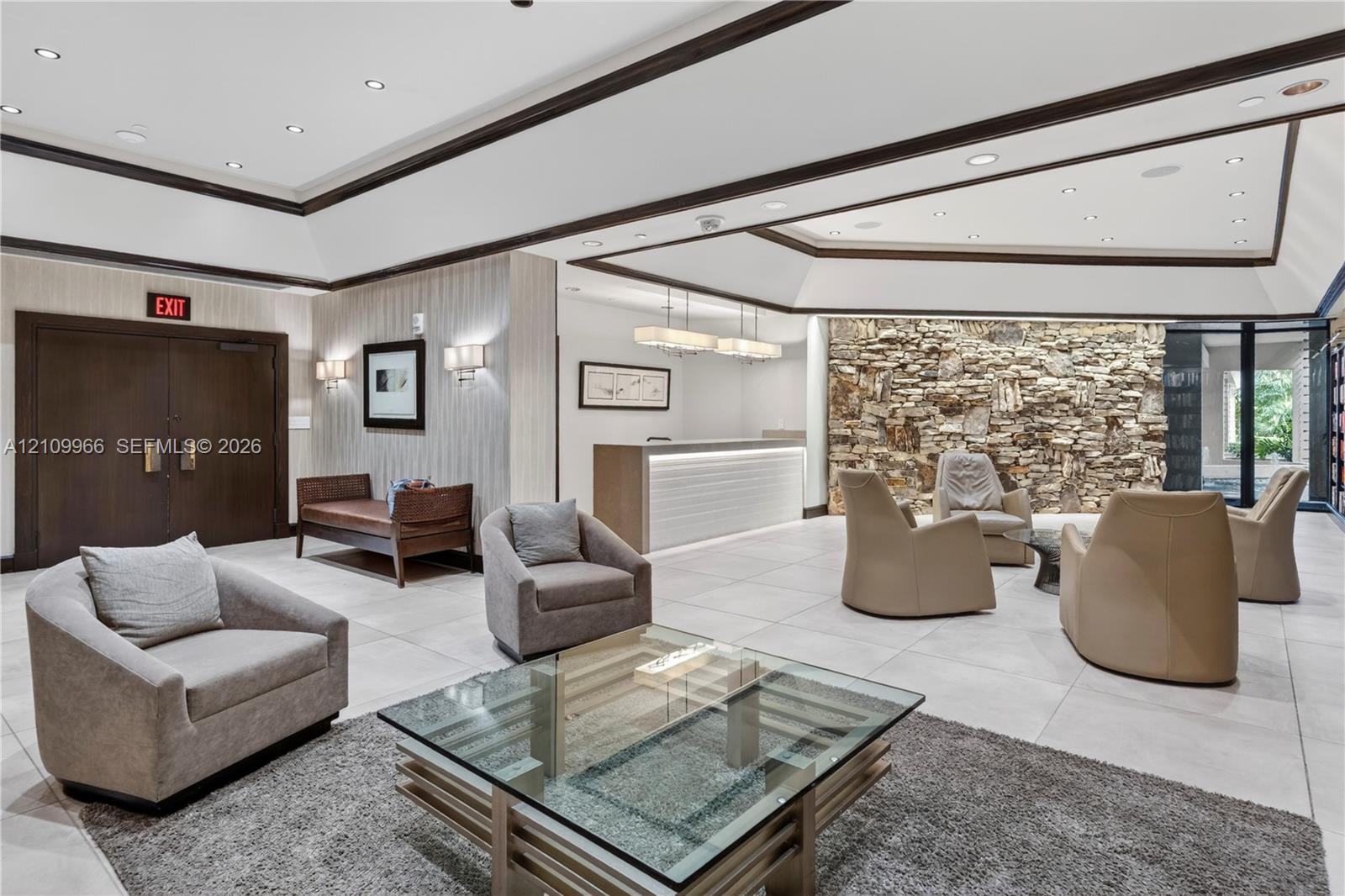 Reception area featuring an expansive tray ceiling, stone-accented wall, recessed lighting, tile flooring, and custom built-in service desk