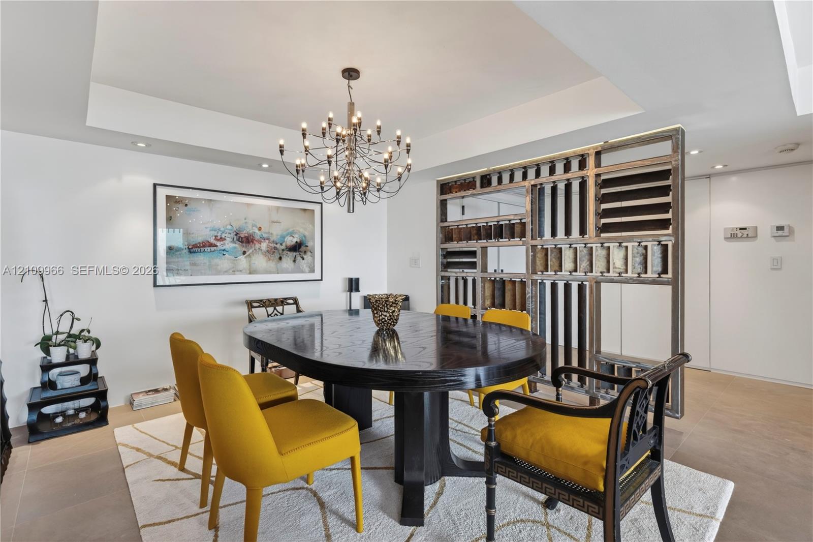 Tray ceiling with recessed lighting, multi-arm metal chandelier, and a custom decorative open-frame metal partition Tray ceiling with recessed lighting, multi-arm metal chandelier, and a custom decorative open-frame metal partition