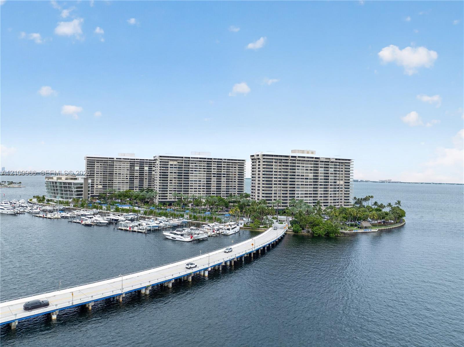 Waterfront high-rise community featuring a private marina, paved causeway access, and established tropical landscaping