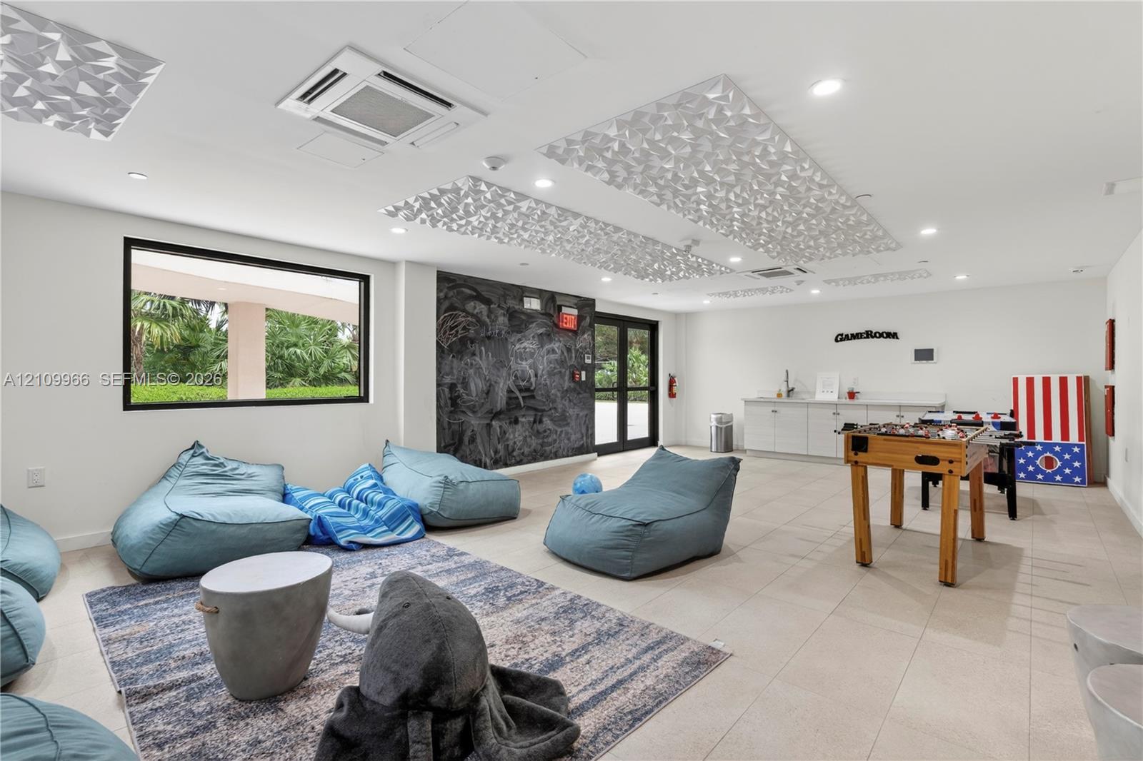 Spacious interior featuring recessed lighting, decorative ceiling acoustic panels, large-format tile flooring, a dark textured accent wall, and built-in cabinetry with a countertop
