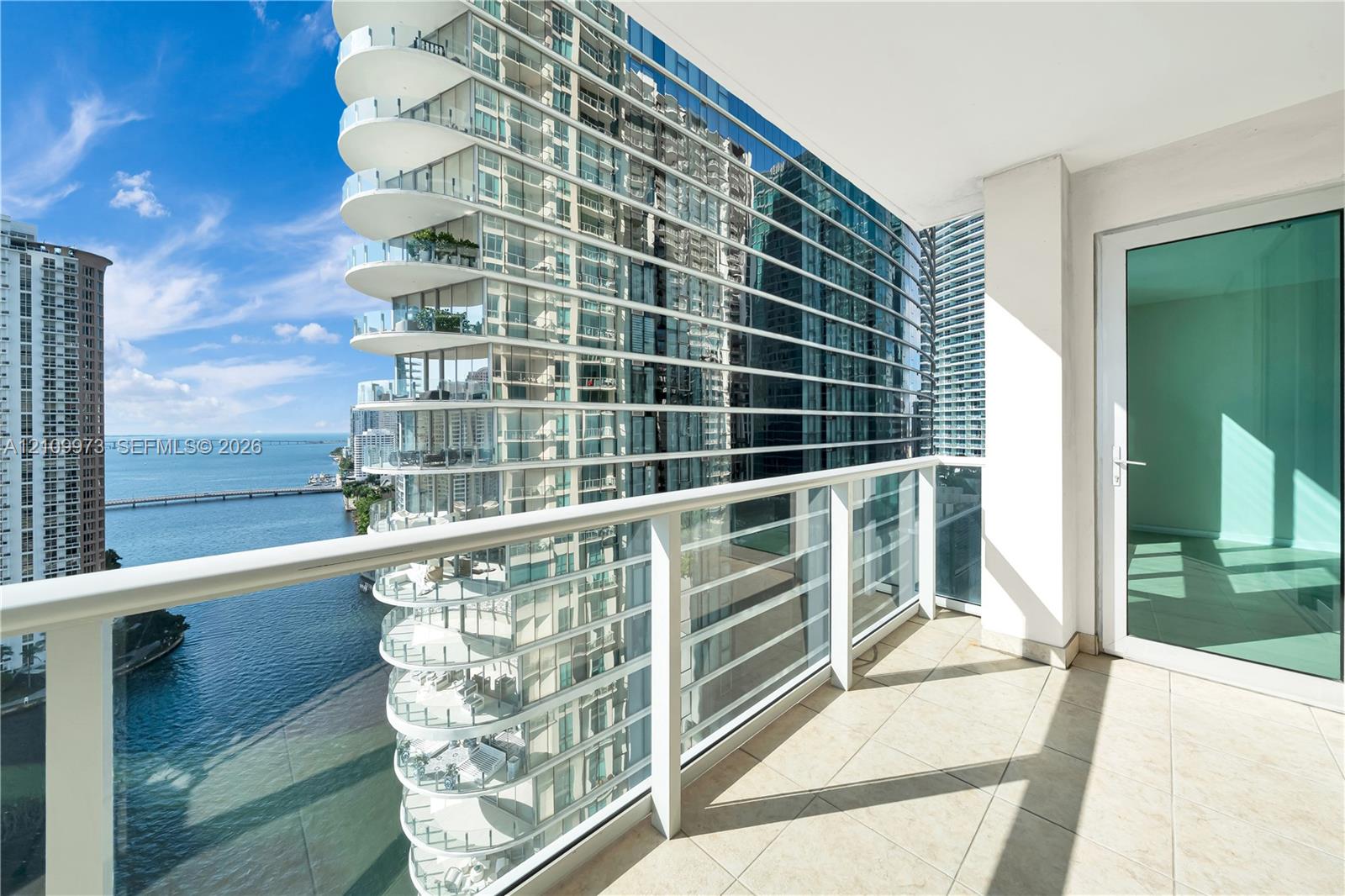 Covered balcony featuring tile flooring and a glass-paneled railing
