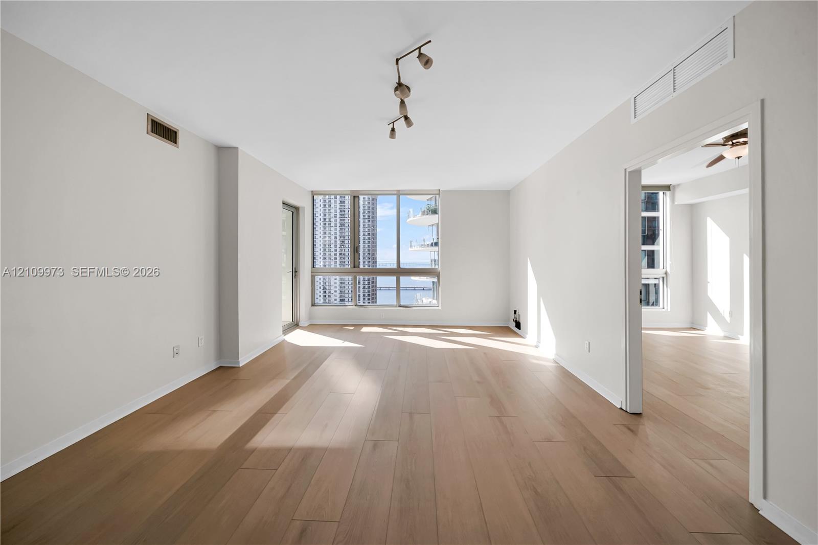 Open-concept living space featuring wood-finish flooring, floor-to-ceiling windows, and multi-directional track lighting