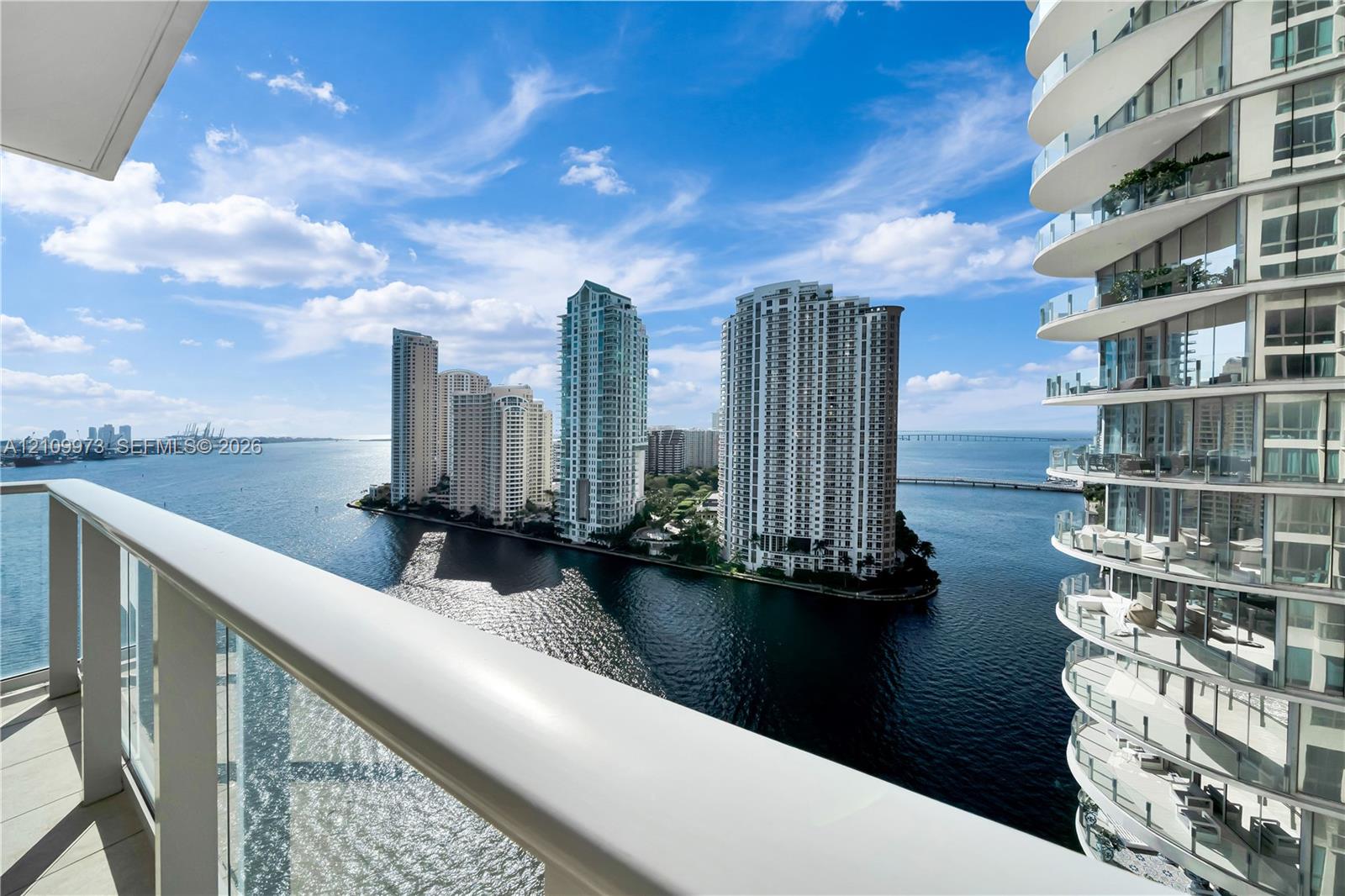 Covered balcony with glass-paneled railing overlooking the waterfront and cityscape Covered balcony with glass-paneled railing overlooking the waterfront and cityscape