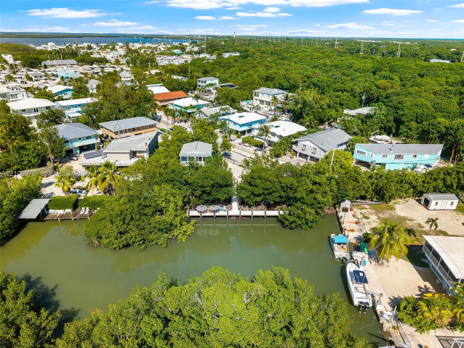 Aerial perspective of canal-front property featuring a private boat dock, natural vegetation, and direct water access