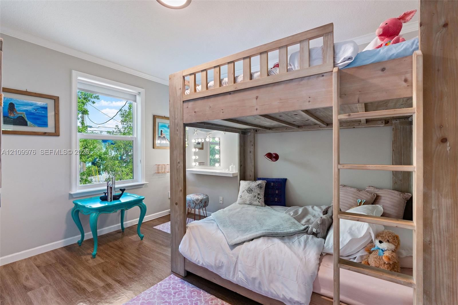 Bedroom featuring wood-finish flooring, a large window with exterior greenery, and a built-in wall-mounted shelf