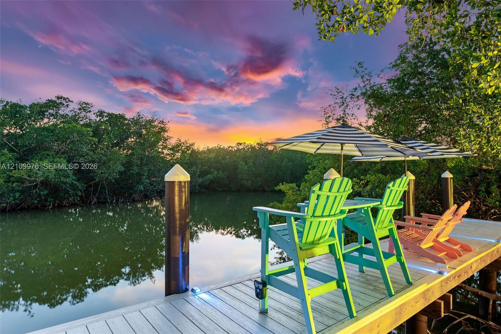 Private dock featuring composite decking, integrated surface lighting, and cylindrical mooring pilings set against a backdrop of mature mangroves