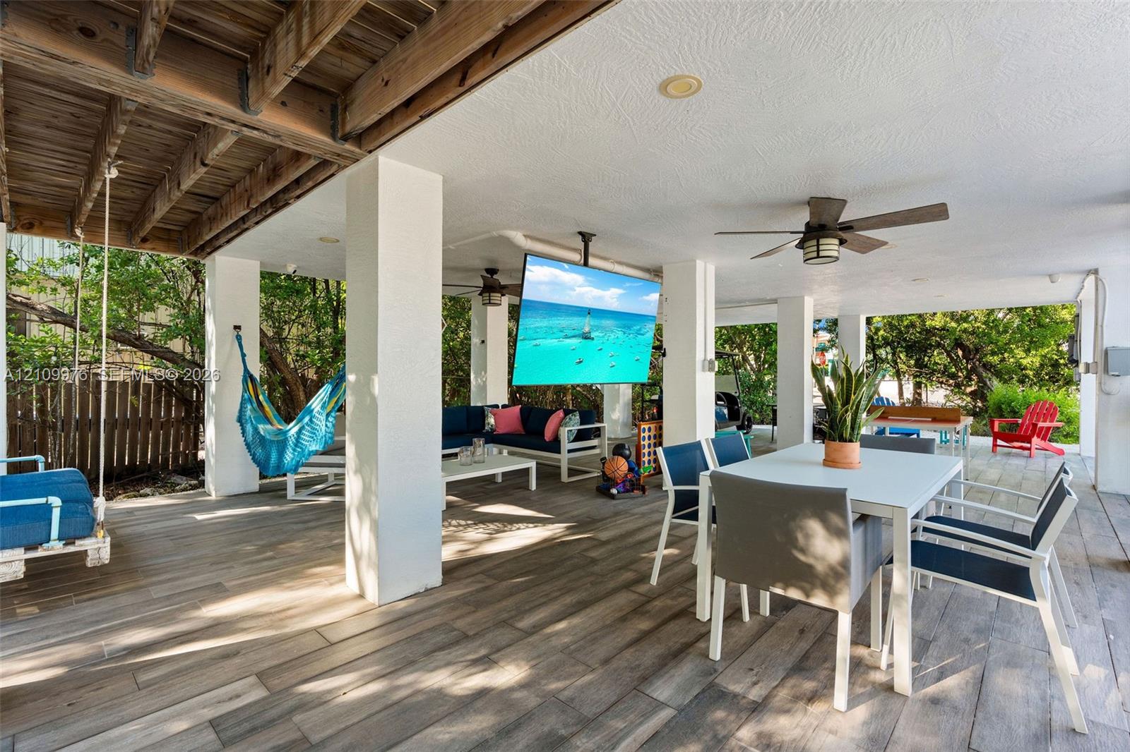 Covered patio featuring wood-finish flooring, recessed lighting, ceiling fans, and a ceiling-mounted television