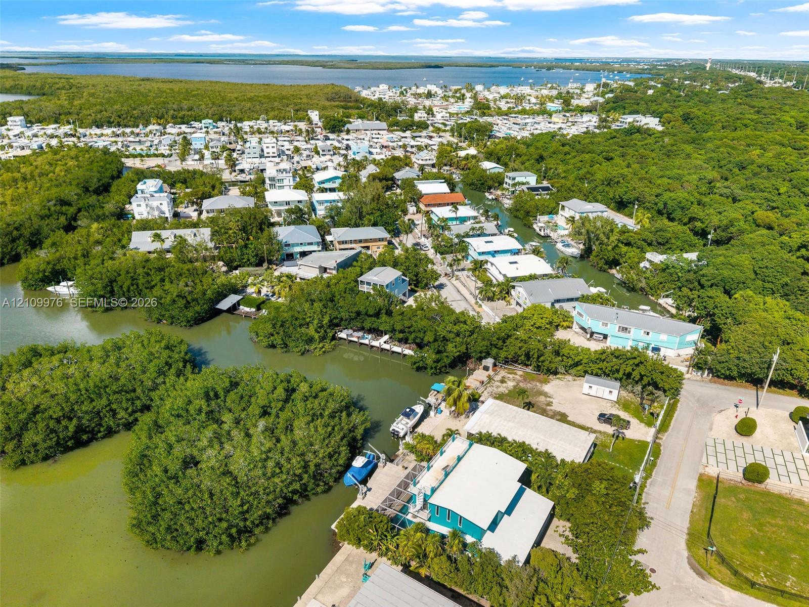 Aerial perspective of a waterfront property featuring direct canal access, private dockage, surrounding mangrove vegetation, and proximity to open bay waters