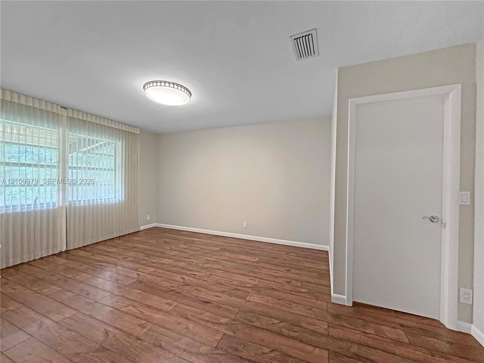 Room featuring wood-finish flooring, neutral wall paint, and a dome flush-mount ceiling light fixture