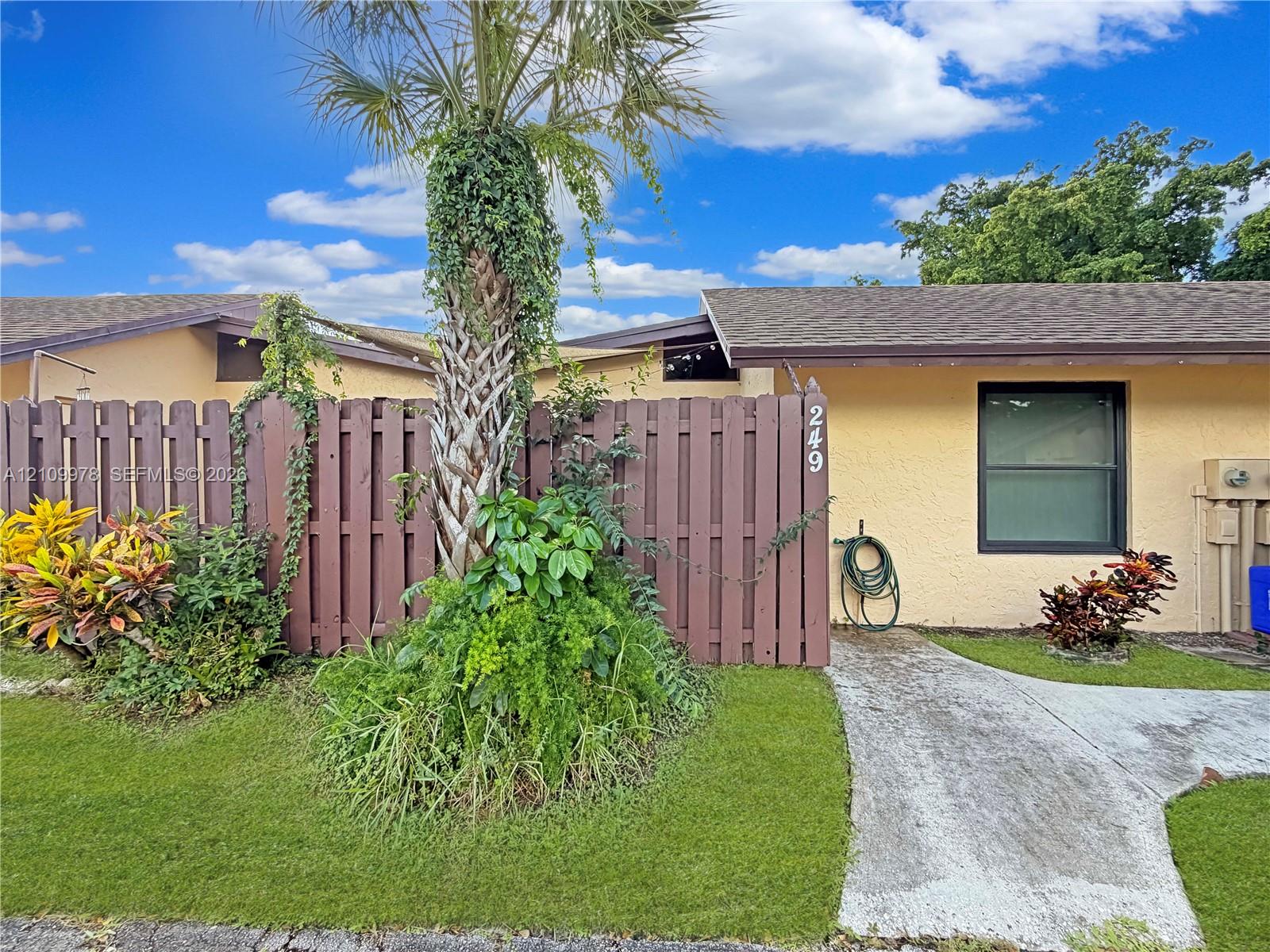 Exterior featuring stucco siding, a shingled roof, a concrete walkway, and a privacy fence Exterior featuring stucco siding, a shingled roof, a concrete walkway, and a privacy fence