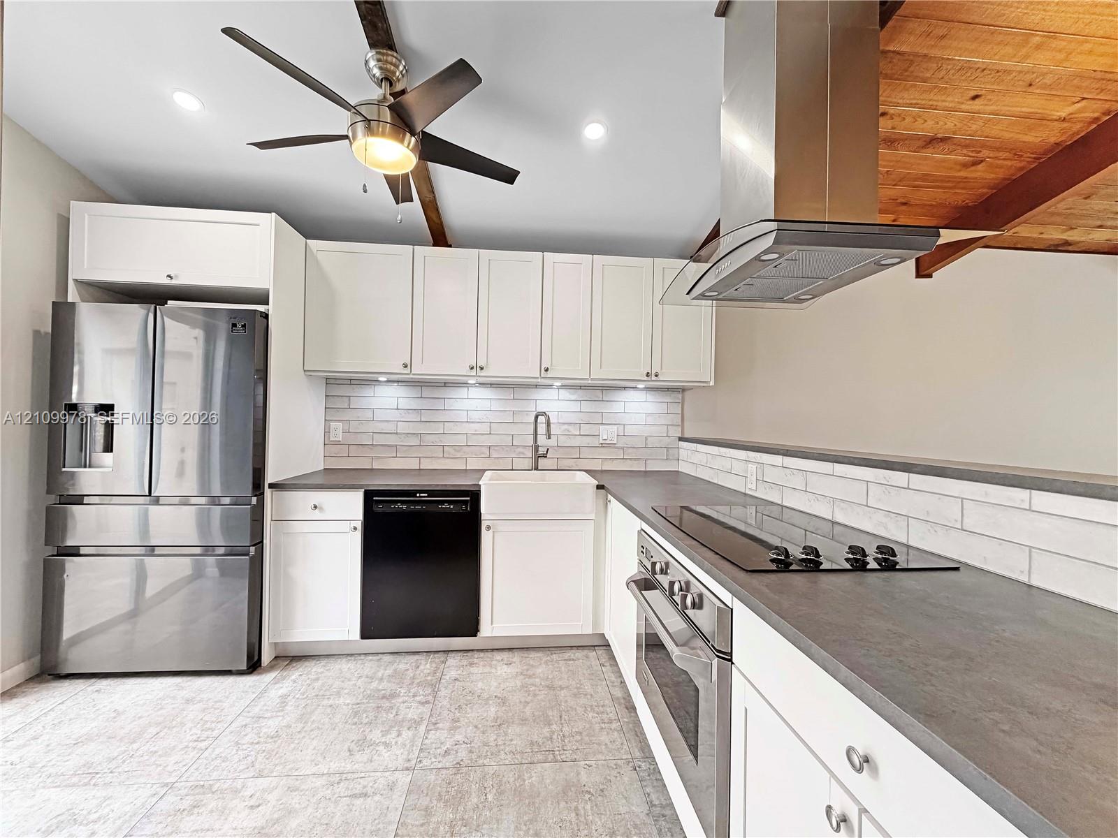 Kitchen featuring shaker-style cabinetry, stainless steel appliances, apron-front sink, brick-style tile backsplash, and wood ceiling beams Kitchen featuring shaker-style cabinetry, stainless steel appliances, apron-front sink, brick-style tile backsplash, and wood ceiling beams