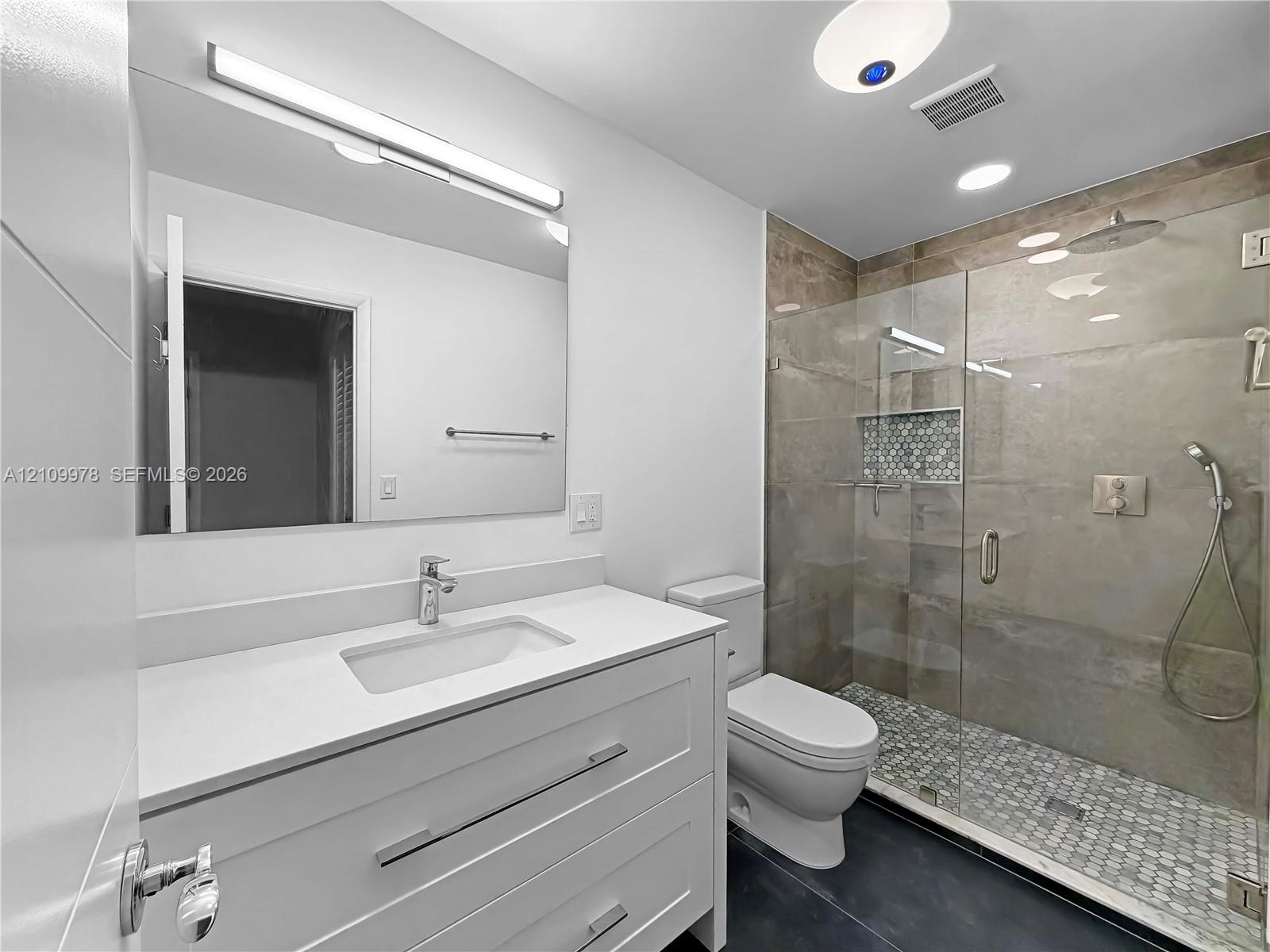 Modern vanity with white cabinetry, rectangular sink, and solid-surface countertop