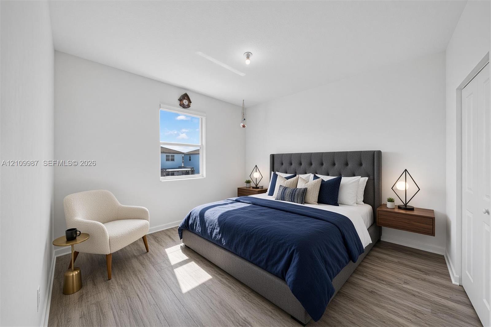 Staged porcelain flooring, neutral walls, single-pane window, and wall-mounted floating wood-finish nightstands